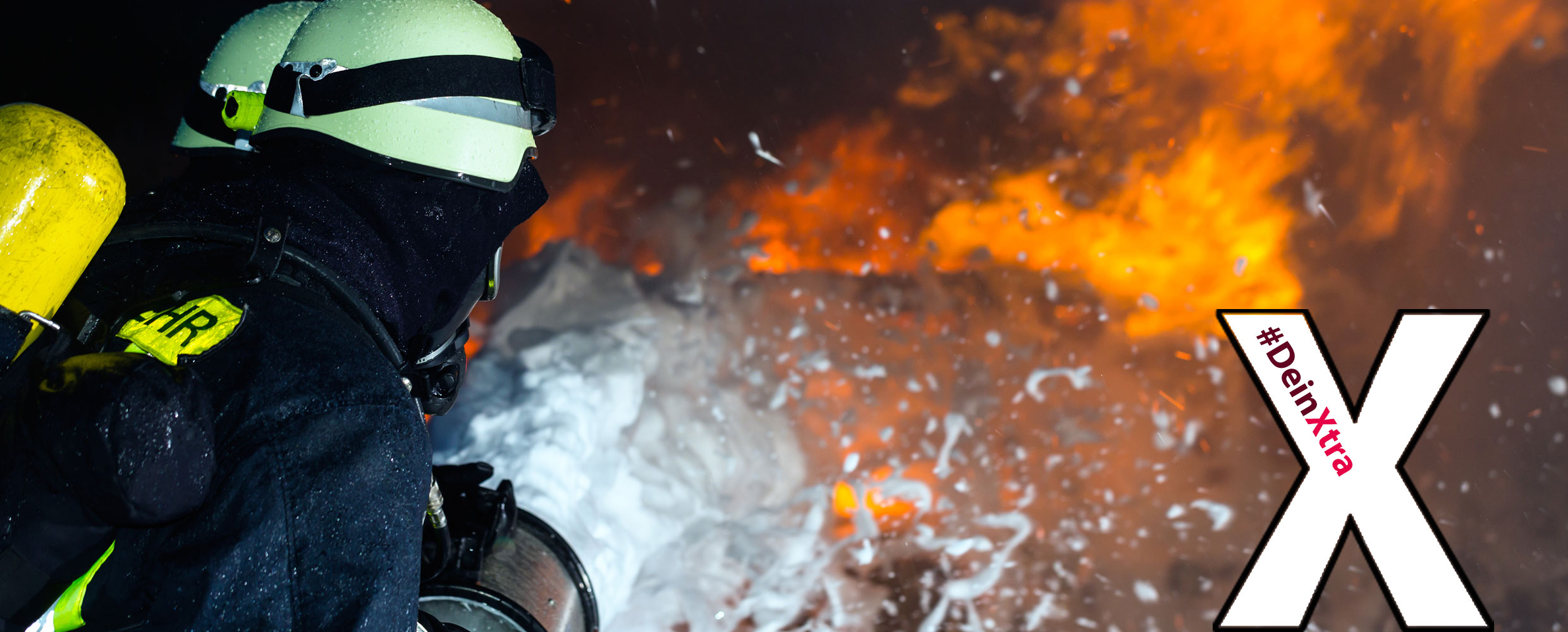 © AdobeStock: Kzenon Bild zeigt Feuerwehrleute beim Löschen eines Brandes und das Logo #DeinXtra.